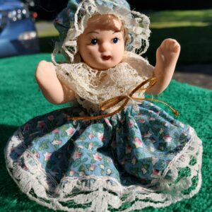 Small Porcelain Doll Wearing Bonnet and Floral Dress with Lace Fringe